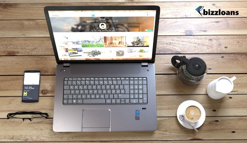 Silver Laptop Next to Coffe Cup Smartphone and Glasses