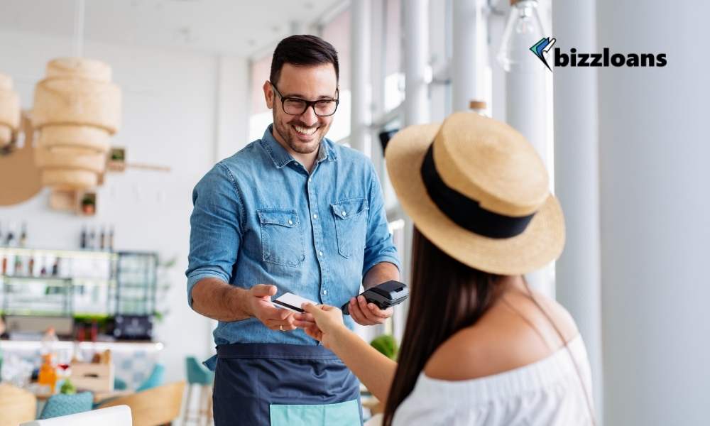 young woman paying by credit card to store owner