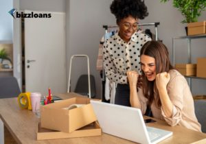 two happy small business owners looking for business loans on laptop